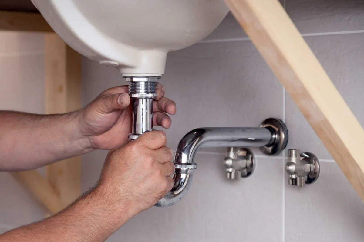 Plumber connecting the drain beneath a bathroom sink