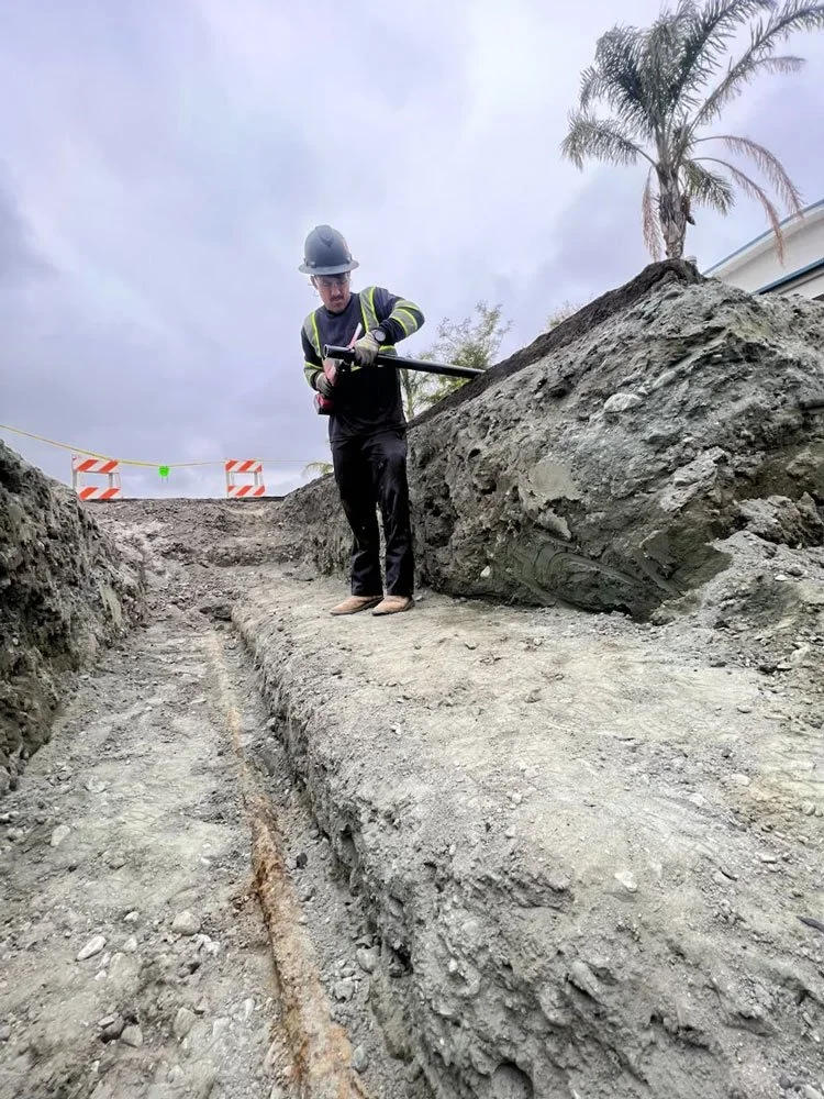 Cruz technician standing beside an excavated water line trench